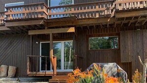 Ein Holzhaus mit Balkon, einer Veranda und einem Garten mit orangefarbenen Blumen.