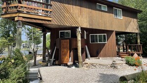 Eine zweistöckige Holzhütte mit Balkon, Eingangstür und einer kleinen Veranda.
