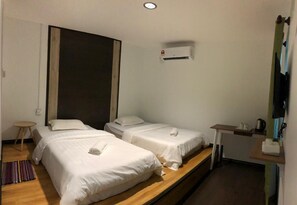A hotel room with two single beds, a small table, a chair, an air conditioning unit, and a kitchenette. - OYO HOME 90667 Chen Room Bs (Semporna)