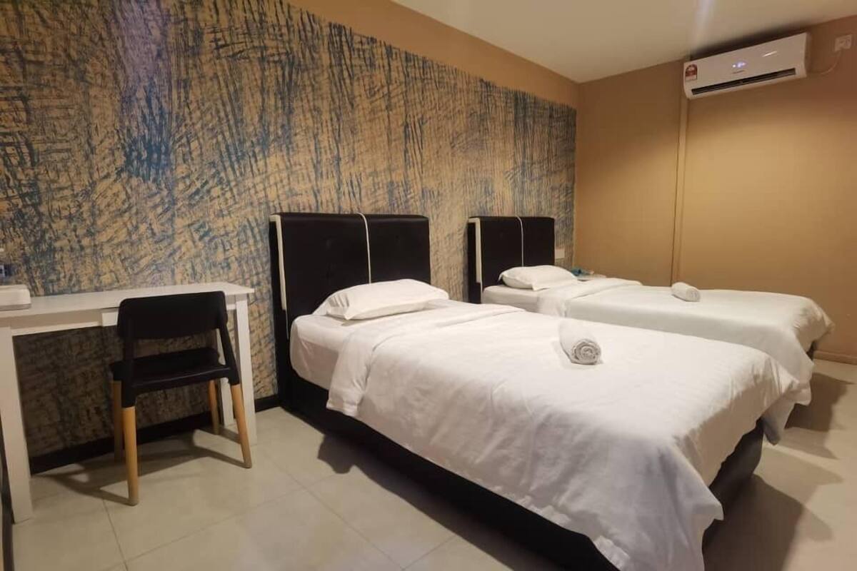 Une chambre d’hôtel avec deux lits, un bureau et une chaise.