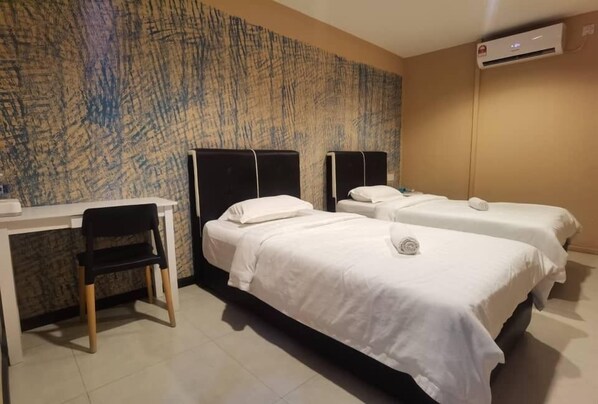A hotel room with two beds, a desk, and a chair.