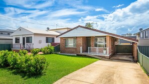 Situated on a well-manicured lawn, this single-story home features a charming brick facade and a cozy porch area.