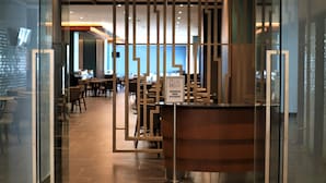 A modern interior with a reception desk, glass partitions, and a dining area with tables and chairs. - KSL Esplanade Hotel (Teluk Panglima Garang)