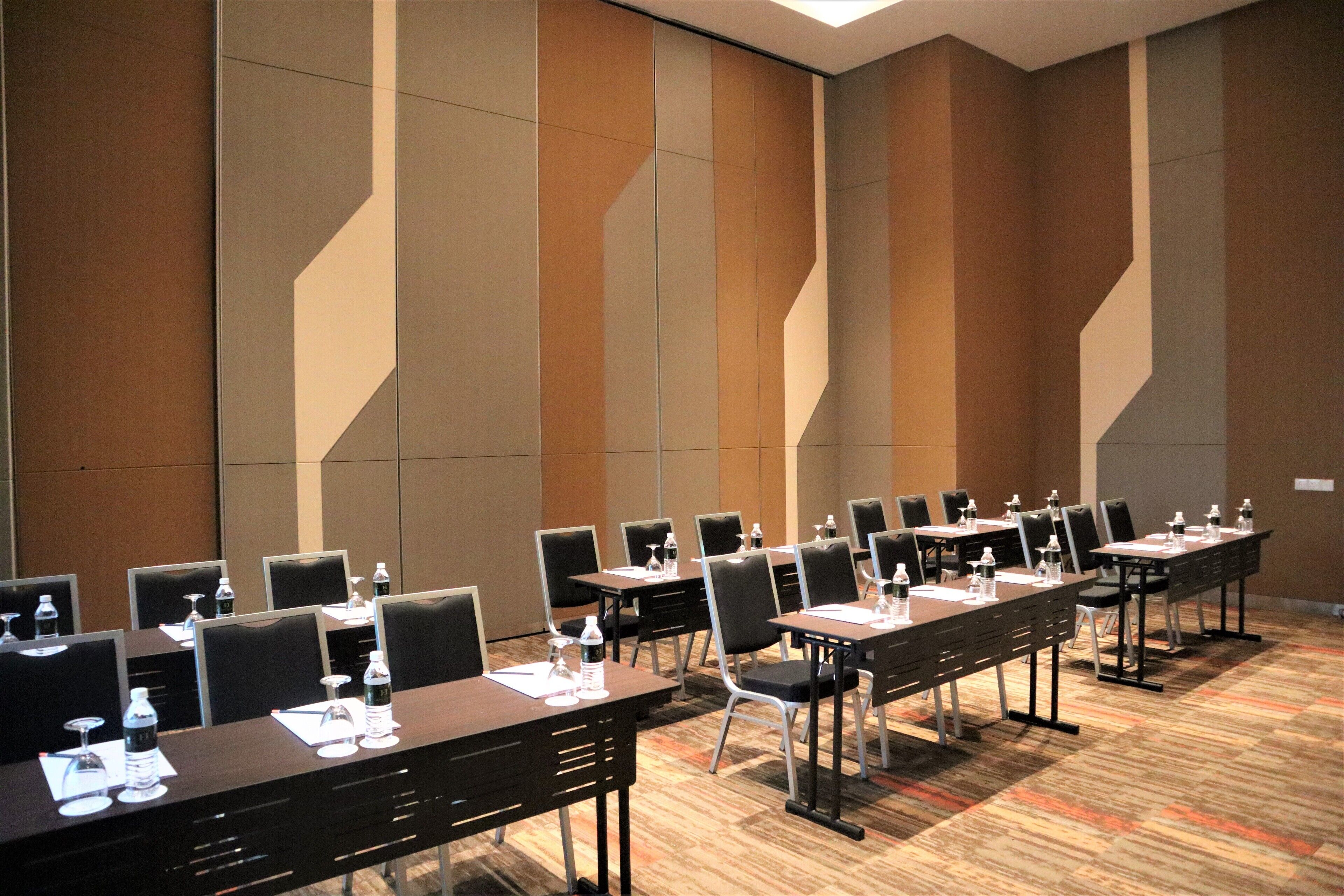 A conference room with multiple tables and chairs, equipped with water bottles and glasses.