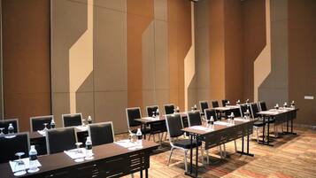 A conference room with multiple tables and chairs, equipped with water bottles and glasses.