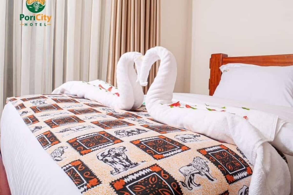 A hotel room with a bed featuring a patterned bedspread and two towels arranged in the shape of swans.