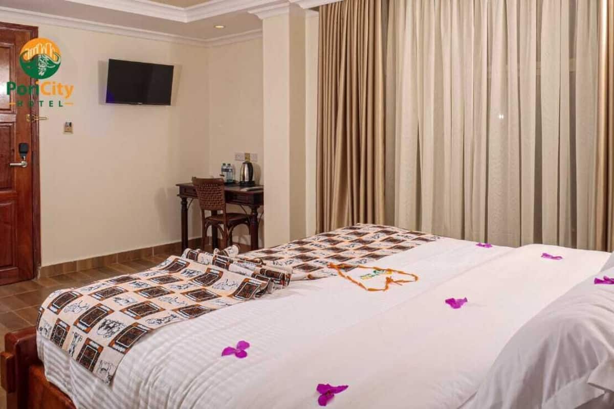A hotel room with a bed, a desk, a chair, a television, and curtains.