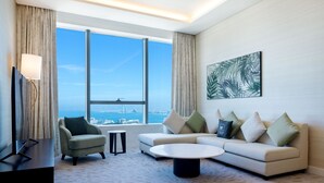 A modern living room with a large window, a sofa, a coffee table, and a TV.