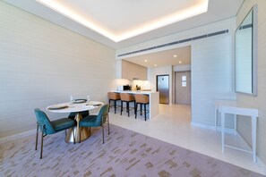 Ein modernes Hotelzimmer mit Essbereich, einer Küche und einem großen Spiegel.