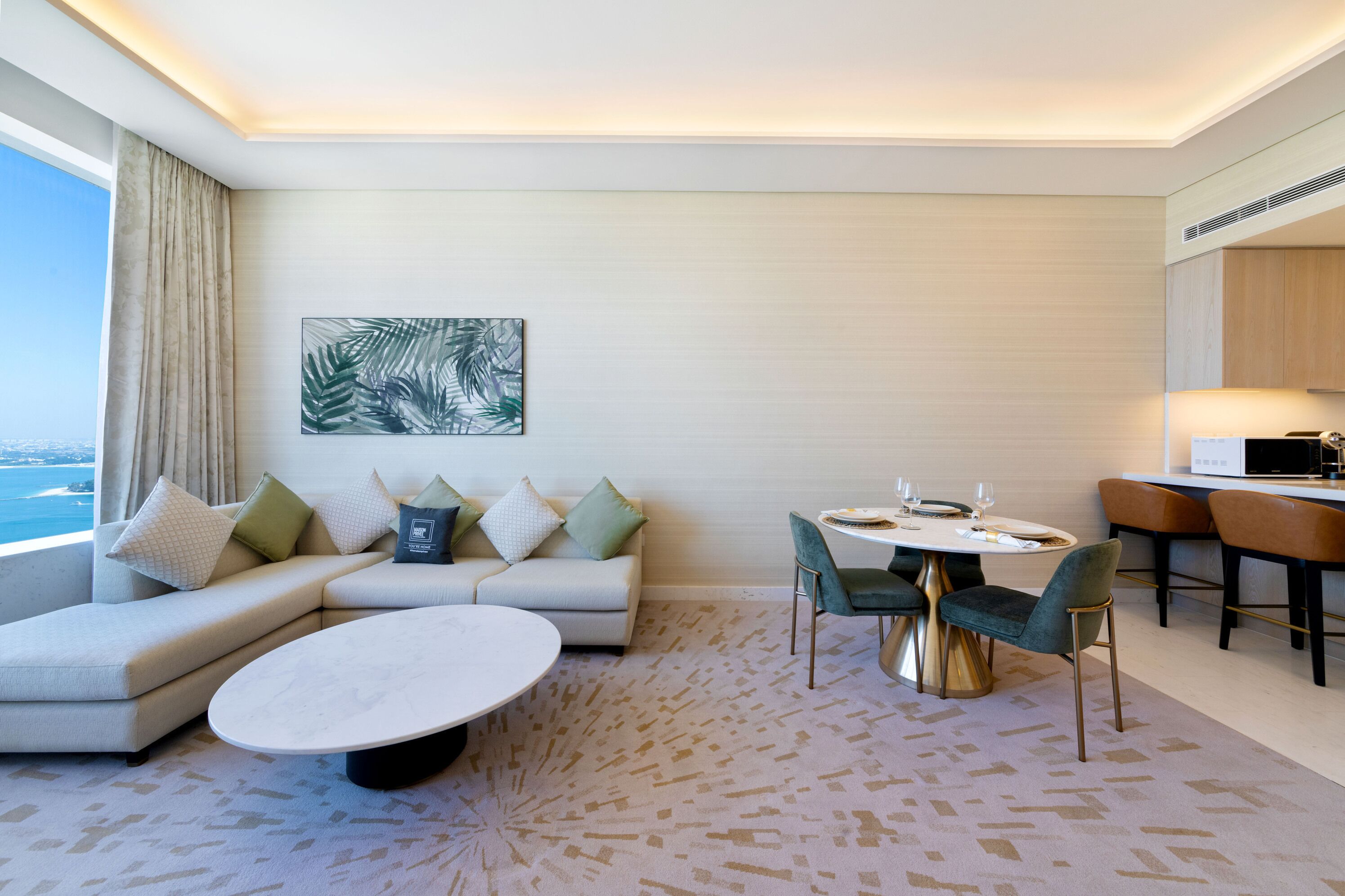 A modern hotel room with a sofa, a round dining table, and a view of the ocean.
