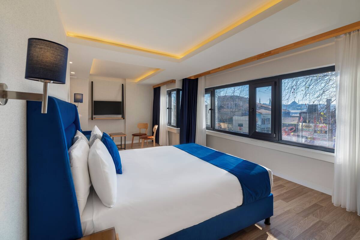 A modern hotel room with a large bed, a desk, and a TV.