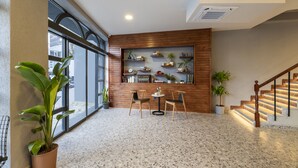 Un vestíbulo amplio con un mostrador de recepción de madera, dos sillas, una mesita y una escalera.