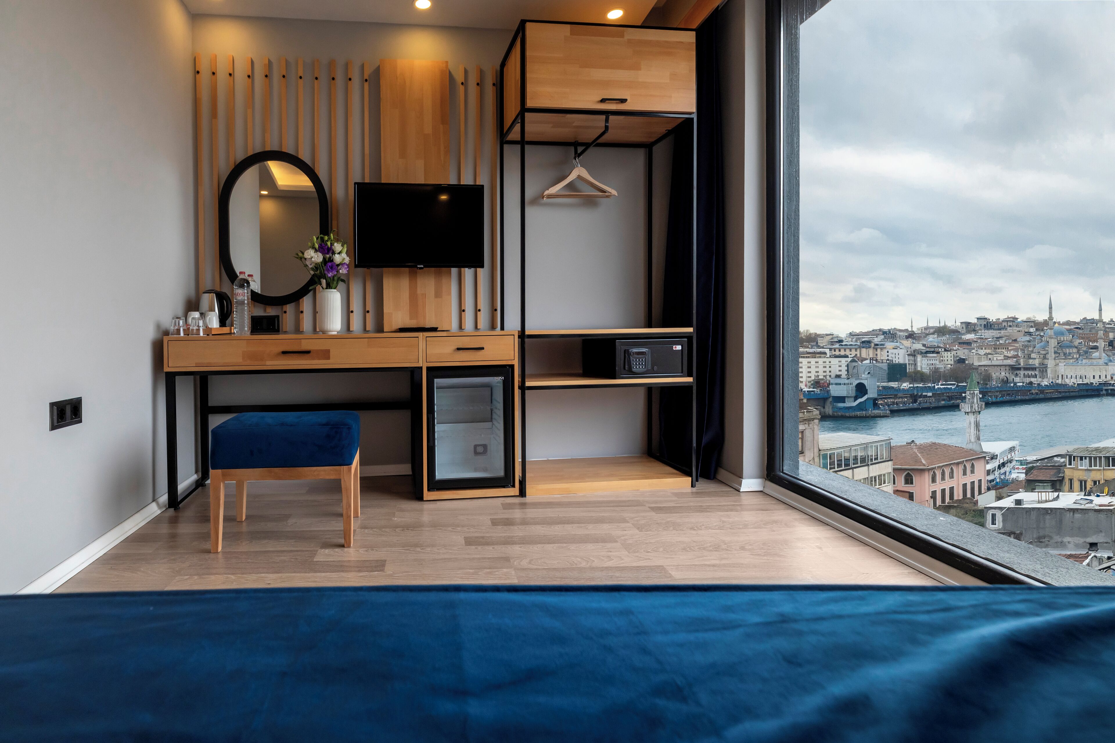 A modern bedroom with a large window, a desk, a chair, and a bed.