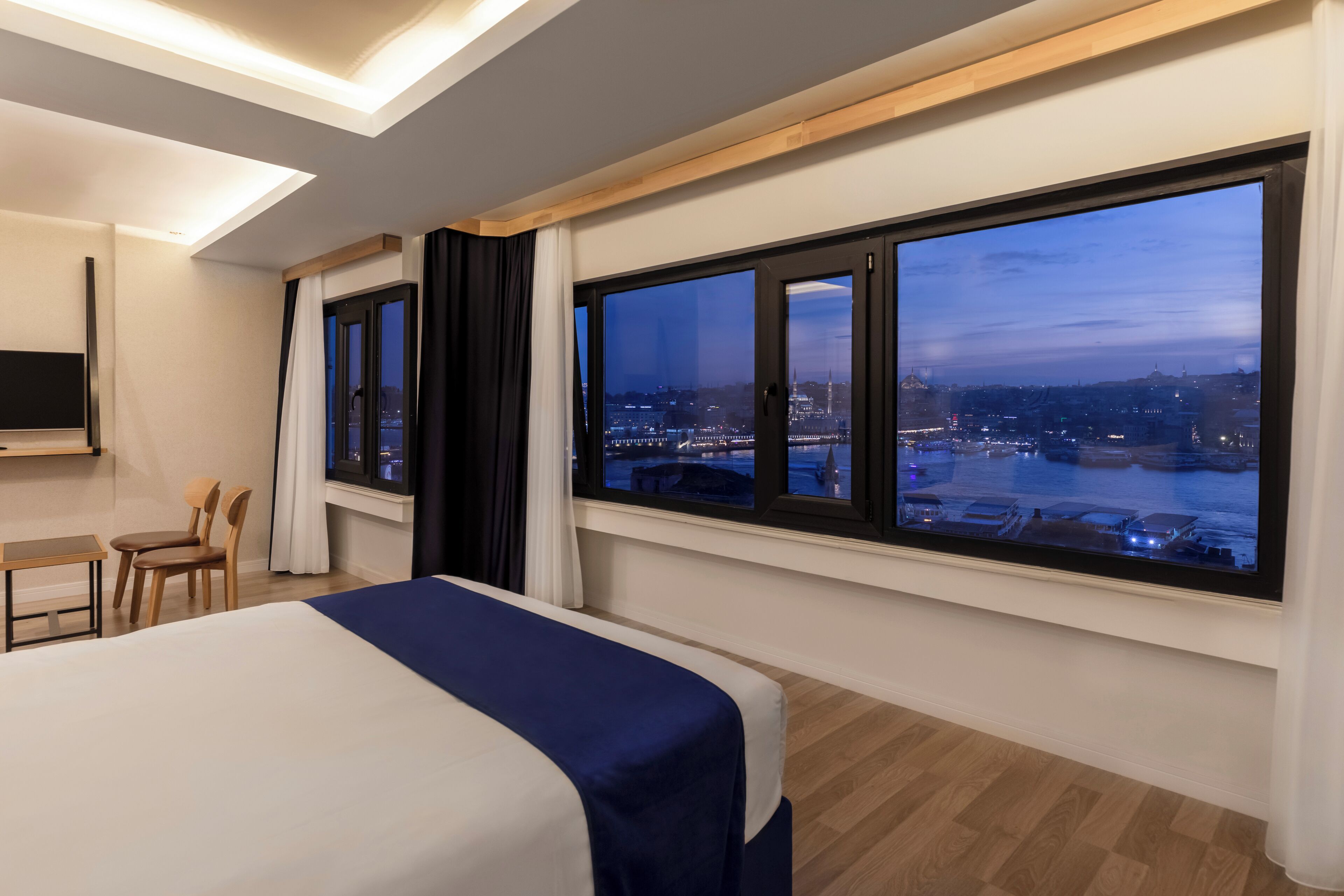Una habitación de hotel moderna con una cama grande, un escritorio y un televisor.