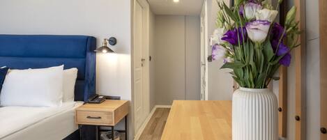 Habitació d'hotel amb un llit, una taula de nit, una làmpada i un vas amb flors.
