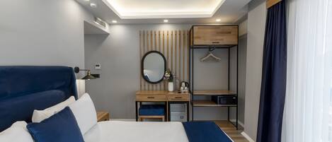 Una habitación de hotel moderna con una cama grande, una mesita de noche y un escritorio con un espejo y perchero.