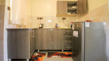 Una cocina compacta con gabinetes de madera, un refrigerador y una cafetera.