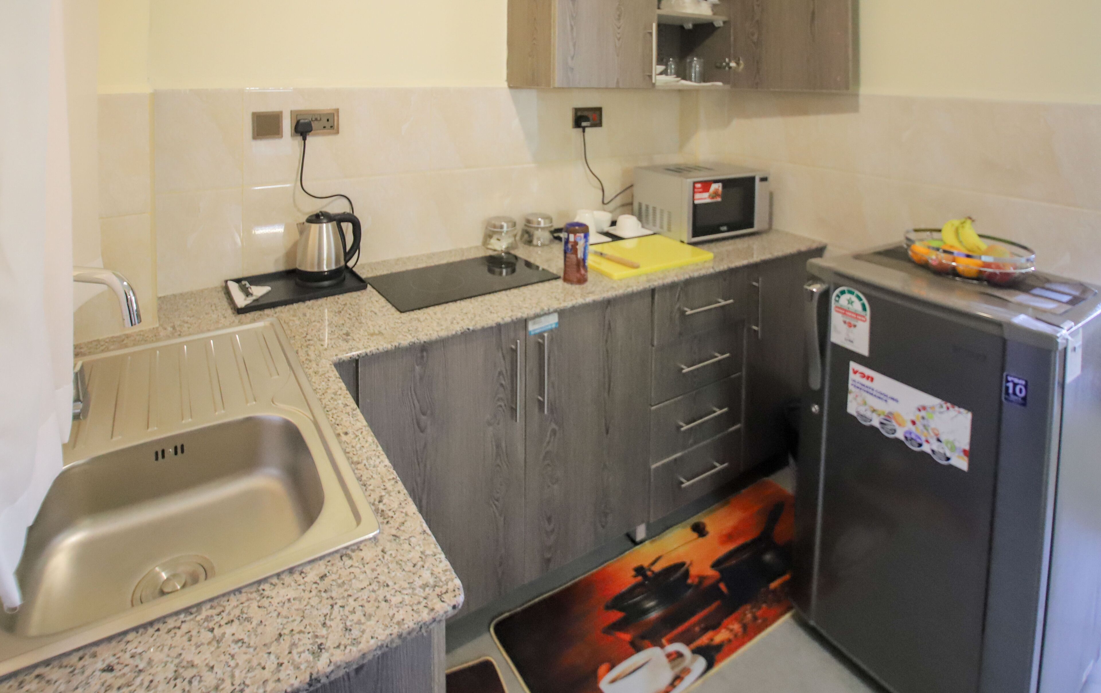 Een kleine keuken met een spoelbak, een magnetron en een koelkast.