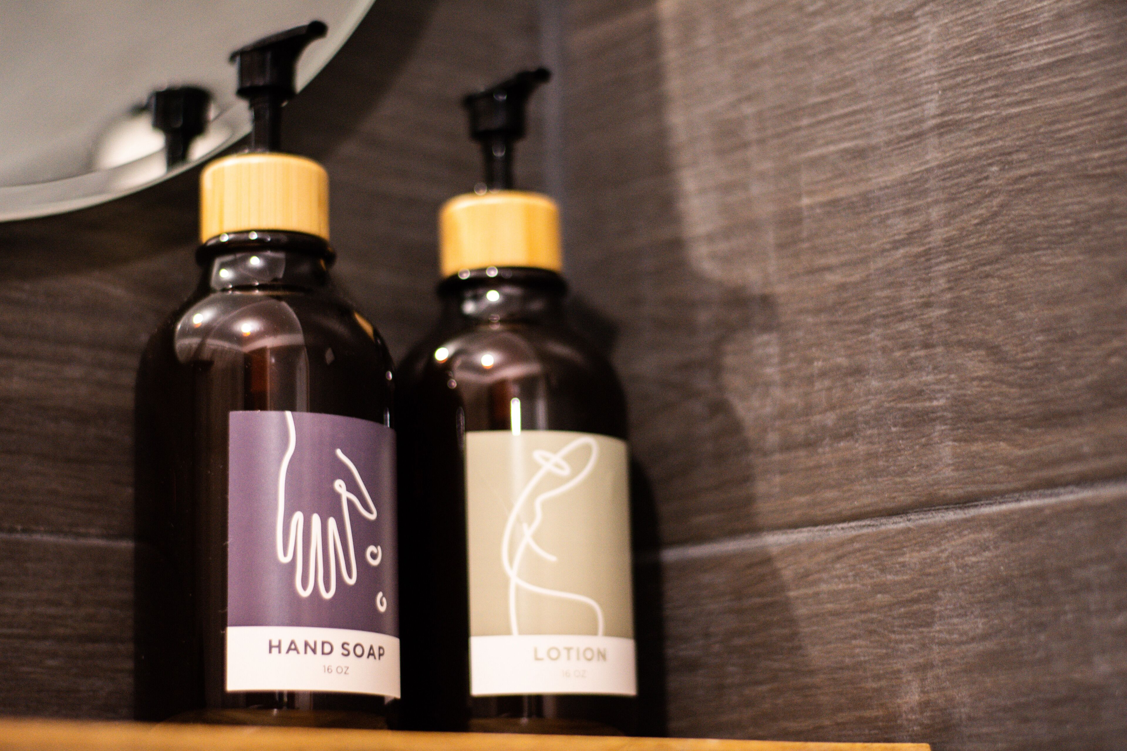 Two bottles of hand soap and lotion on a wooden shelf.