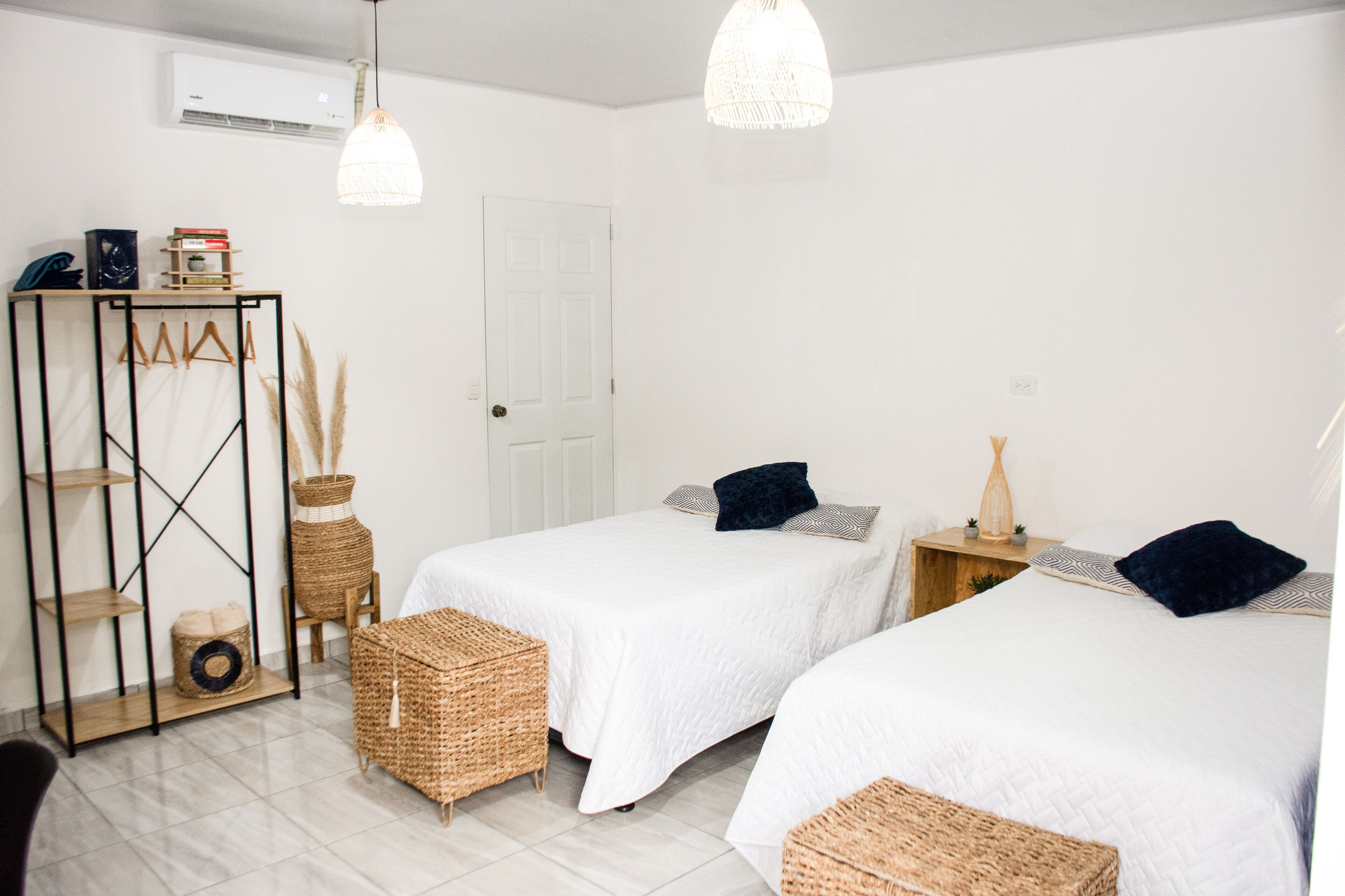A room with two beds, a wardrobe, and a hanging light fixture.