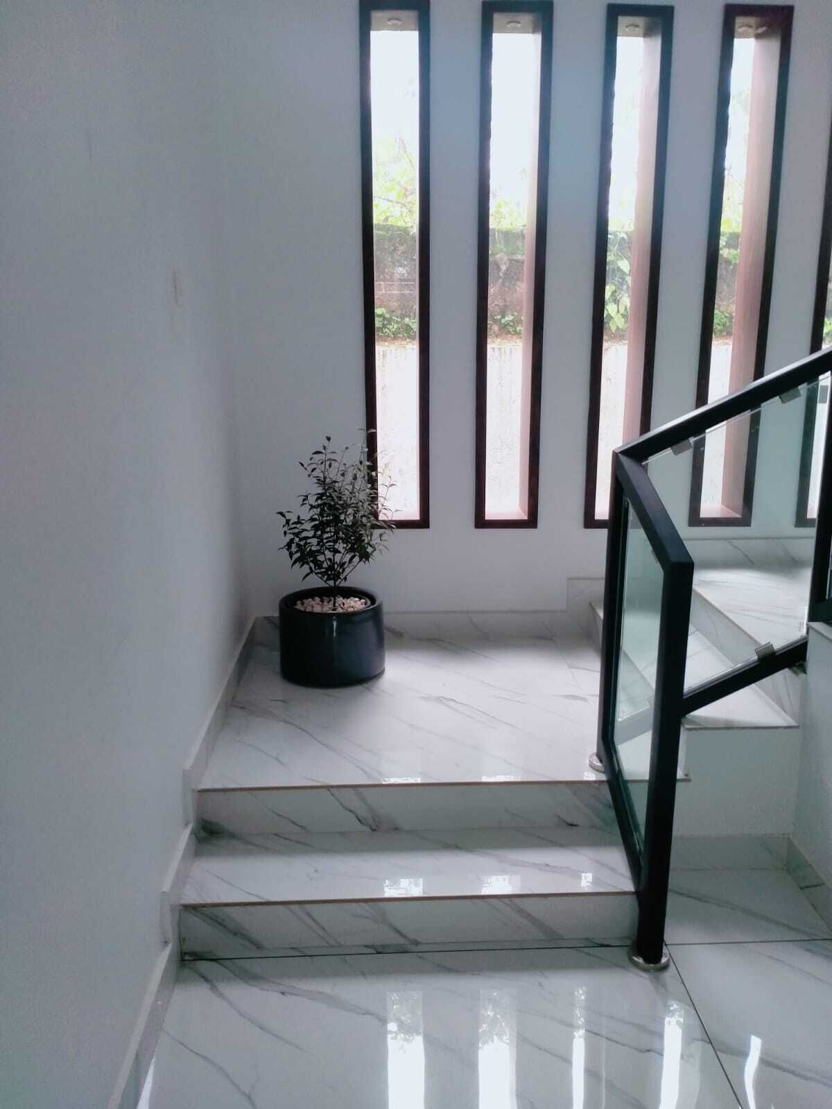 A staircase with a glass railing, a potted plant, and large windows with vertical blinds.