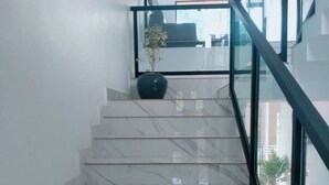 A marble staircase with glass railings leading to an upper floor. - The Lavender Resort (Vythiri)
