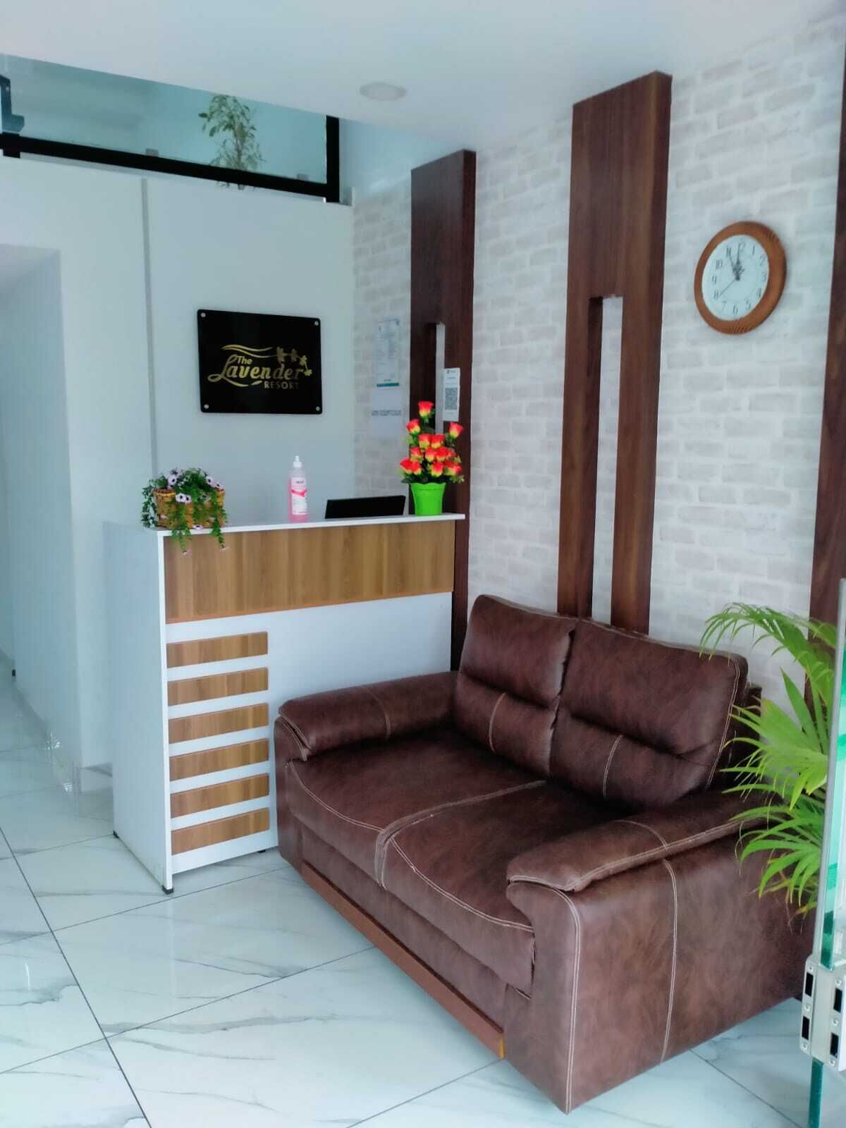Una zona de recepción con un mostrador de madera, un sofá de cuero marrón, un reloj en la pared y un letrero que dice "The Lavender Resort".