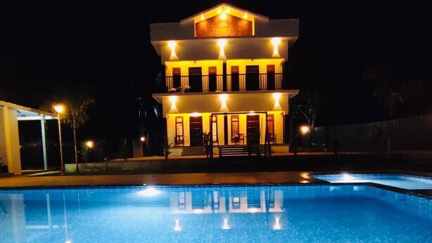 A multi-story hotel with a swimming pool in the foreground. - The Lavender Resort (Vythiri)