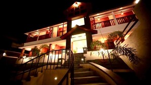 A multi-story building with a staircase leading to the entrance, surrounded by potted plants. - The Lavender Resort (Vythiri)
