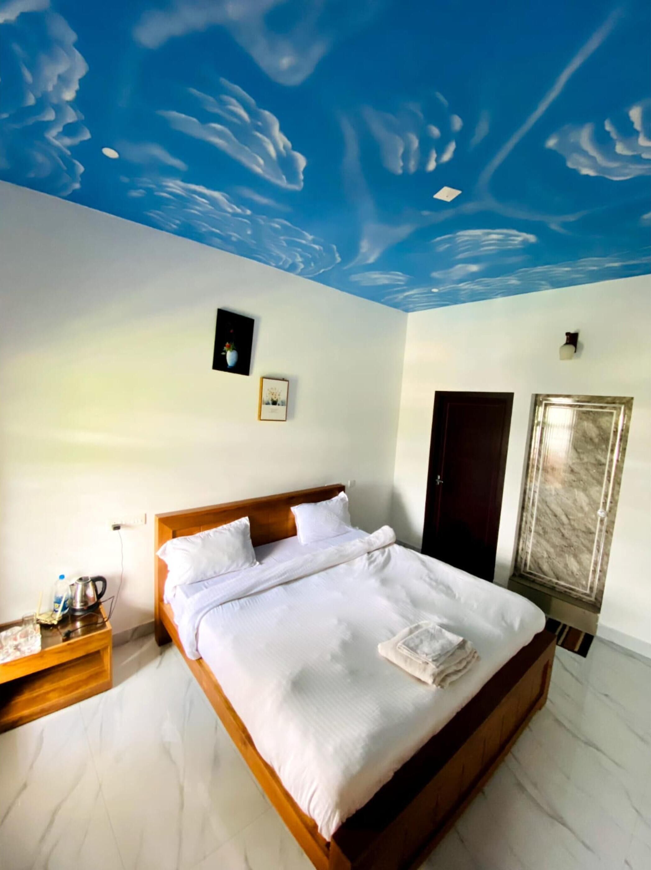 A bedroom with a bed, a nightstand, a door, and a marble wall.