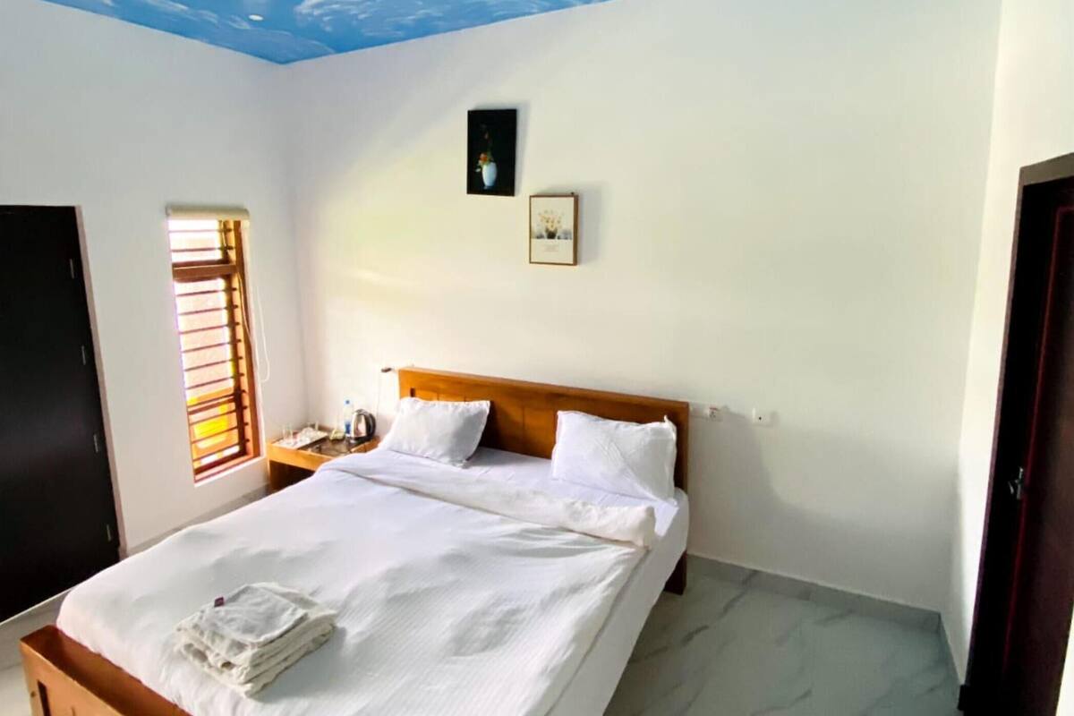 Ein Schlafzimmer mit einem Bett, einem Nachttisch, einem Fenster mit Jalousien und einer Tür.