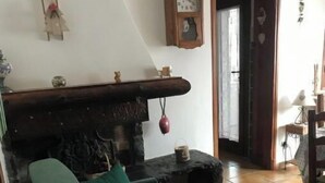 Ett vardagsrum med en grön soffa, en steneldstad och en träklocka på väggen.