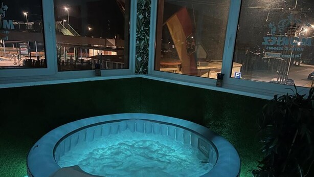 Un jacuzzi en un rincón con vista a un edificio y una planta cerca.