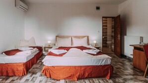 Una habitación de hotel con dos camas, un armario de madera, un escritorio y un radiador.