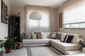 A modern living room with a sectional sofa, a floor lamp, and a potted plant. - Villa in the heart of Tuscany (Rigutino)