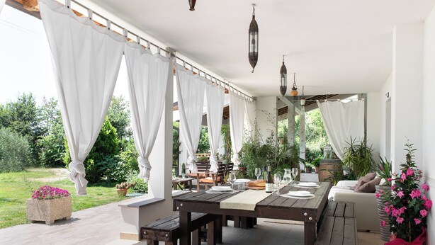 An outdoor dining area with a wooden table, benches, and white curtains. - Villa in the heart of Tuscany (Rigutino)