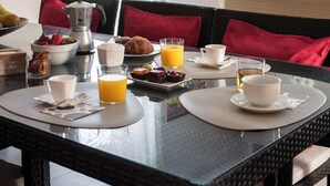 A breakfast table set with a variety of food items, including fruits, pastries, and beverages, in a well-lit room with a view of the outdoors. - Villa in the heart of Tuscany (Rigutino)