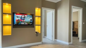 Una sala de estar moderna con un televisor de pantalla plana montado en la pared, iluminación empotrada y piso de madera.