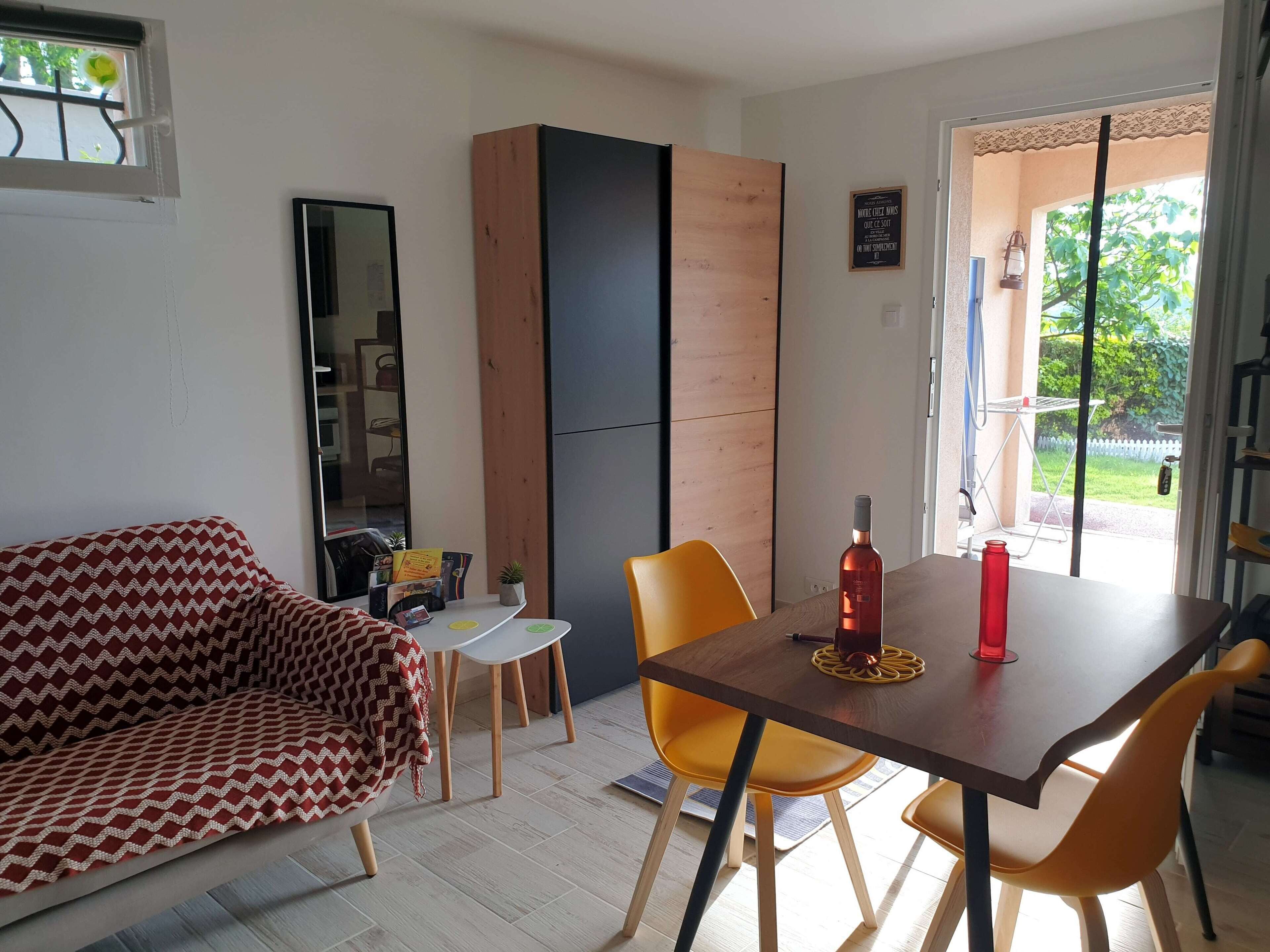 A modern living room with a sofa, a dining table with chairs, a small side table, and a wooden cabinet.