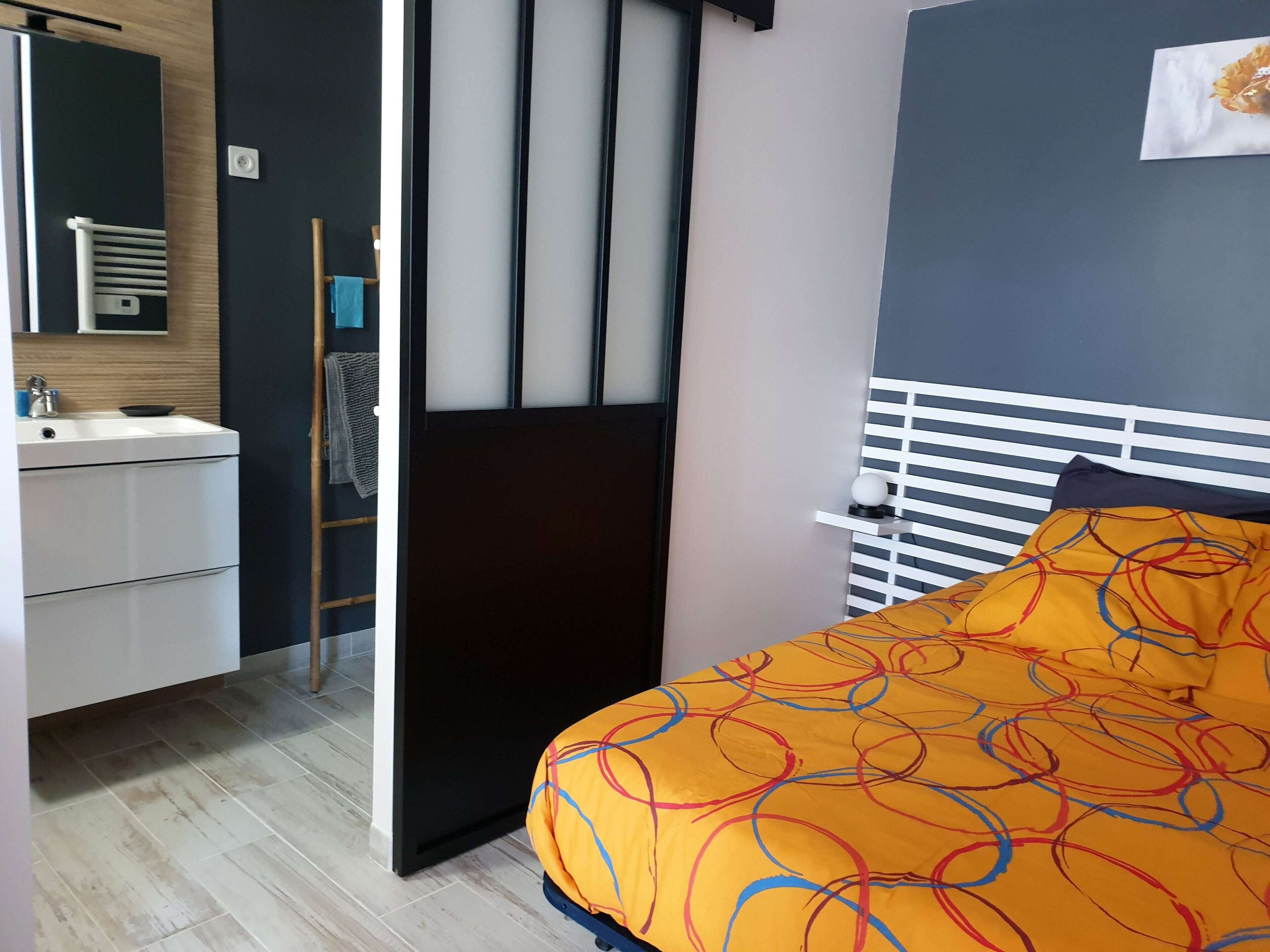 A bedroom with a bed, a bedside table, a nightstand, a dresser, a mirror, and a window.