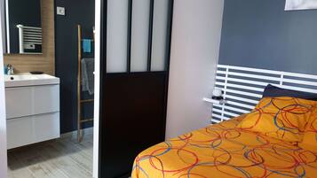 A bedroom with a bed, a bedside table, a nightstand, a dresser, a mirror, and a window.