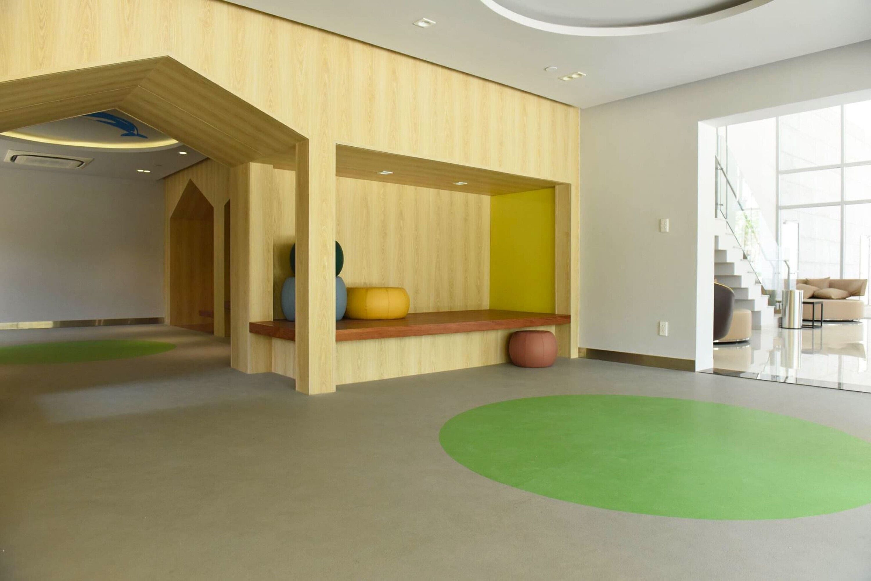 A modern interior with a wooden bench, a green carpet, and a staircase in the background.