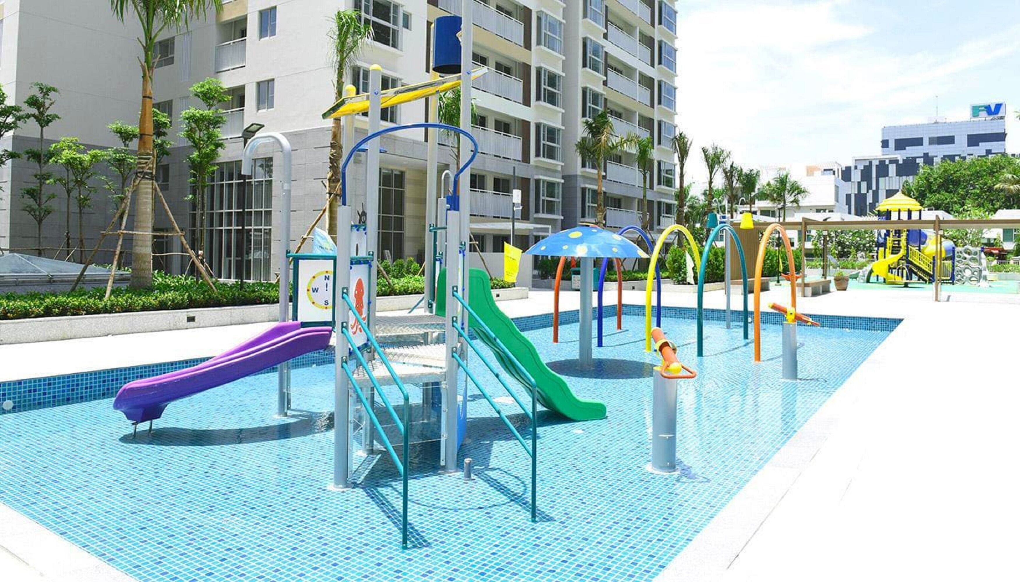 A swimming pool area with multiple slides and a water play structure.