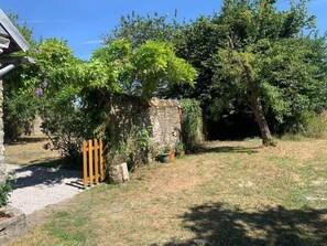 A garden with a stone wall, a wooden gate, and various plants.