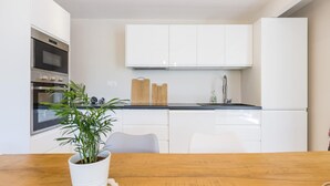 A modern kitchen with white cabinets, a built-in oven, a sink, and a wooden countertop.