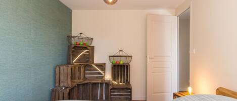 A bedroom with a bed, a hanging light fixture, and decorative baskets on wooden crates.