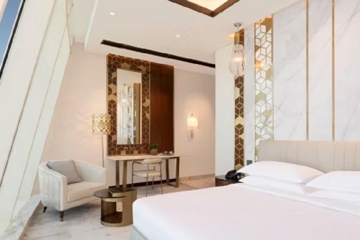 A modern hotel room with a large bed, a desk, and a chair.