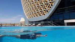 A swimming pool with a modern building in the background. - Velero Hotel Doha Lusail (Doha)