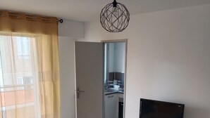A modern living room with a sofa, a coffee table, a TV, and a dining area. - Apartment very close to the sea (Toulon)