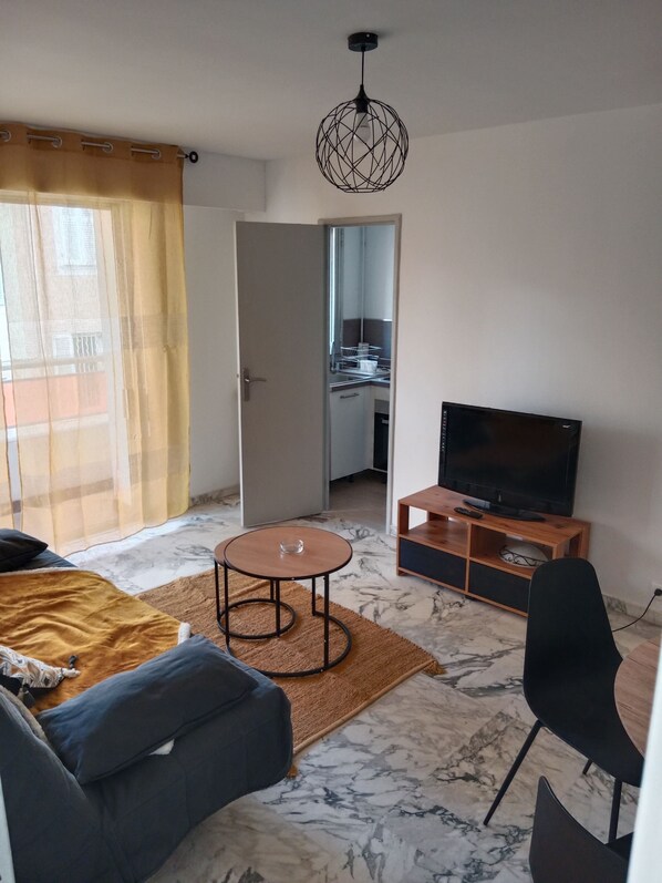 Una sala de estar moderna con un sofá, una mesa de centro, un televisor y un comedor.